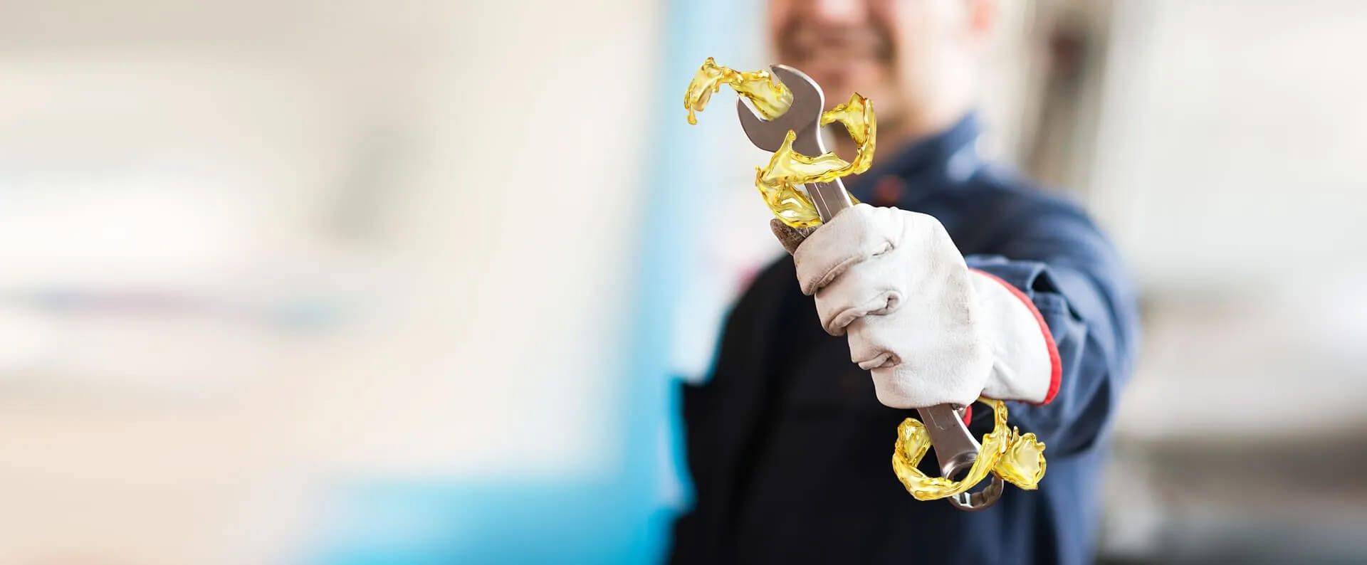 Ein Mann, der ein Werkzeug zeigt, mit Handschuhen.